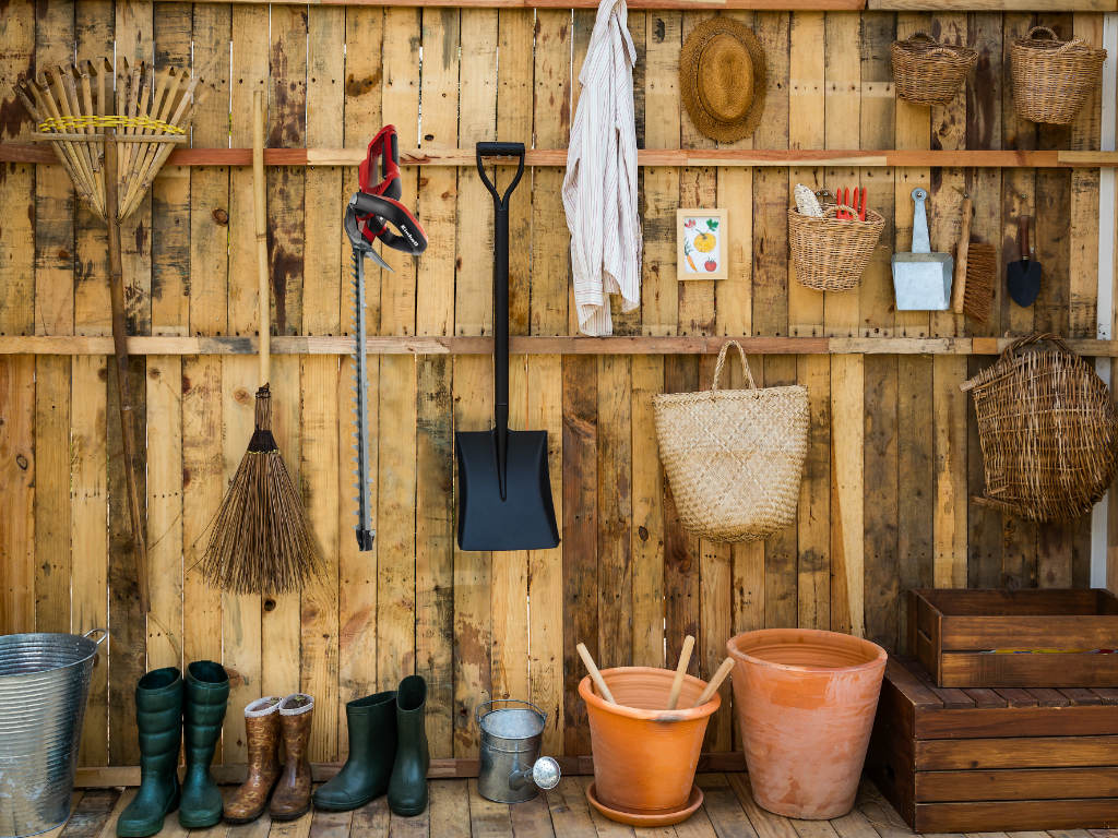 Garden utensils hang and lean on the wall
