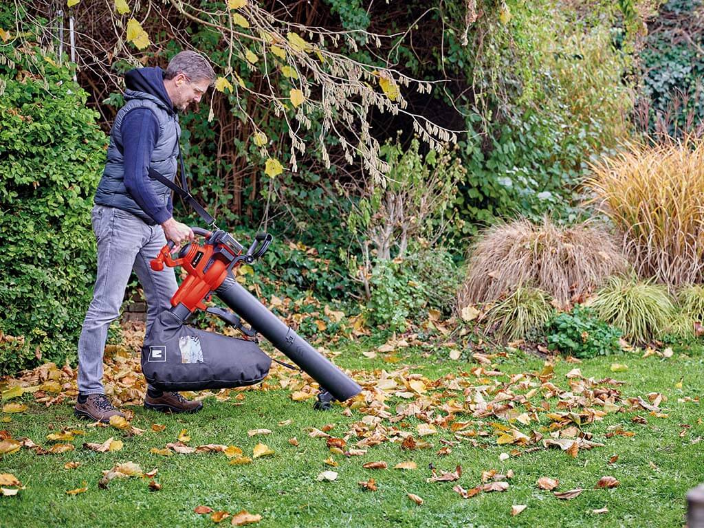 man vacuuming up leaves in the garden