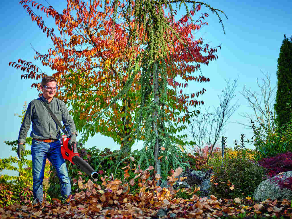 a man blows the leaves off the pavement