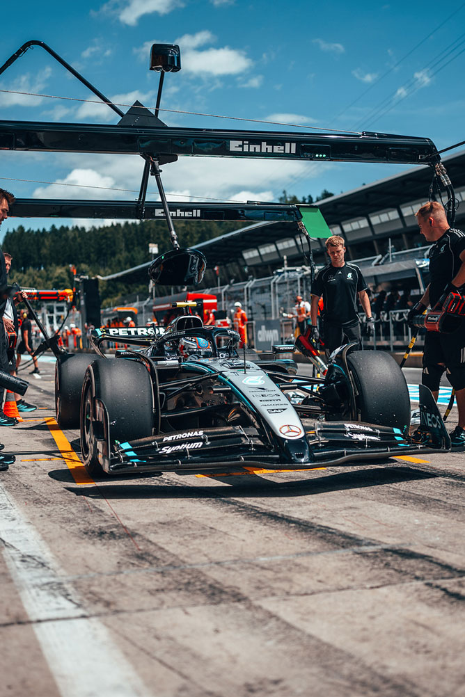 O mașină Mercedes-AMG Formula 1 este în zona de boxe, înconjurată de membri ai echipei sub o structură de garaj Einhell.