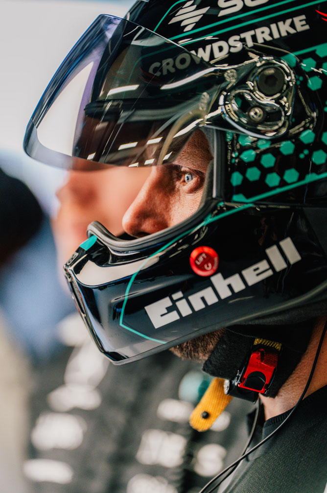 Un membru al echipei Formula 1 poartă cască și se uită concentrat în lateral.