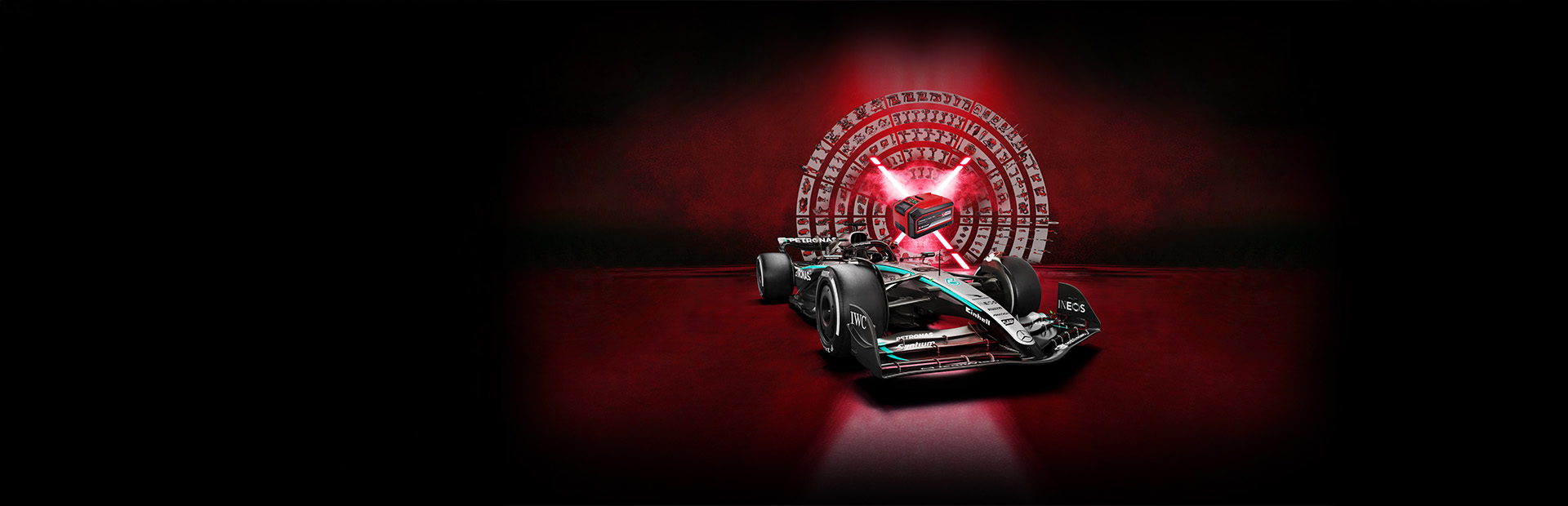 A Mercedes-AMG PETRONAS Formula One race car in front of a red background with a central Einhell Power X-Change battery illuminated by red light beams.