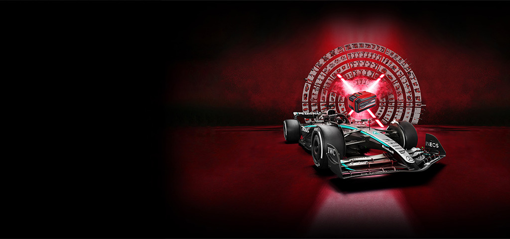 A Mercedes-AMG PETRONAS Formula One race car in front of a red background with a central Einhell Power X-Change battery illuminated by red light beams.