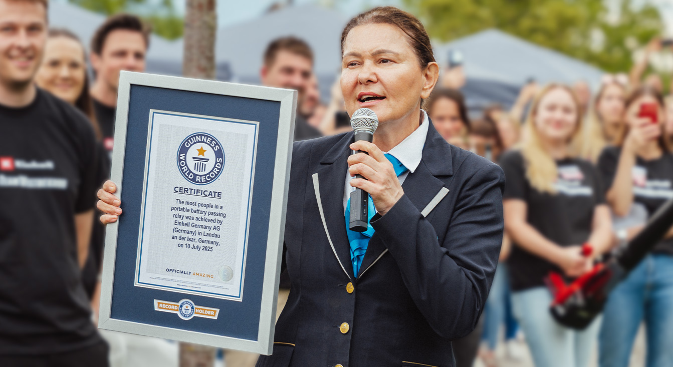 O femeie in tinuta oficiala Guinness tine o diploma pentru recordul mondial la stafeta de acumulatori Einhell.