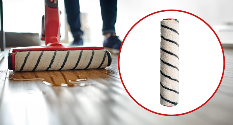 An Einhell cordless hard floor cleaner cleans a wooden floor with a rotating brush roller; next to it is a replacement brush roller.