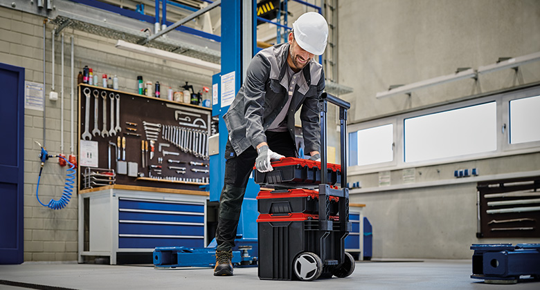 A worker stacks Einhell E-Cases in a workshop.
