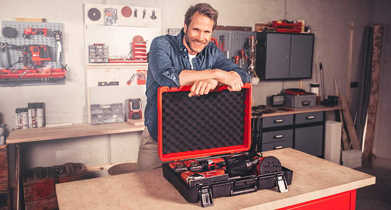 A man presents an open Einhell E-Box in a workshop.