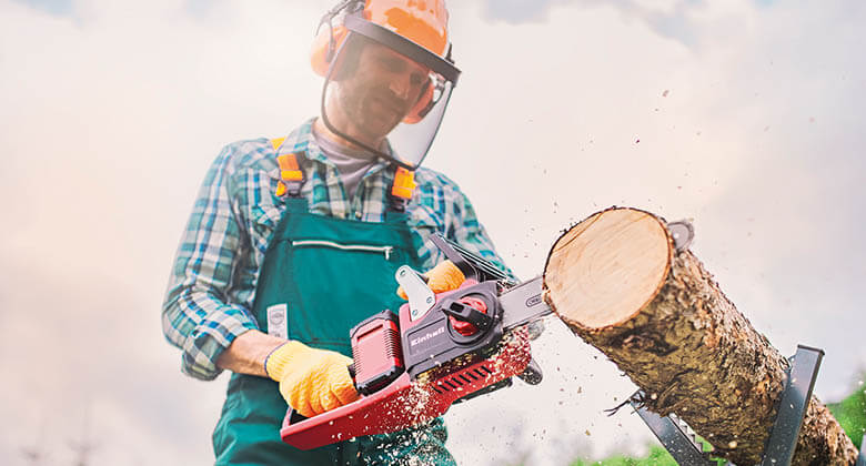 Cutting tree trunk with electric chainsaw side perspective