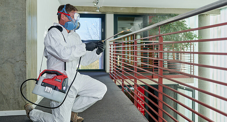 man working with pressure sprayer to disinfect a railing