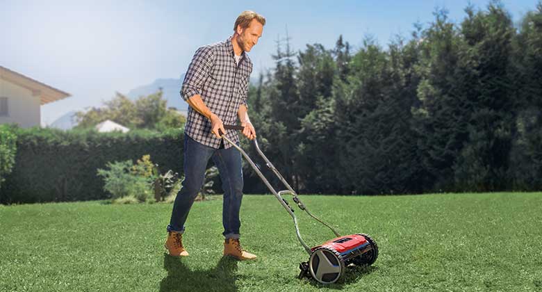 a man uses a hand lawn mower