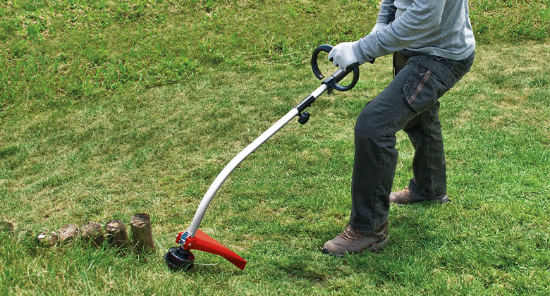 a man is cutting gras with the Einhell Petrol Lawn Trimmer