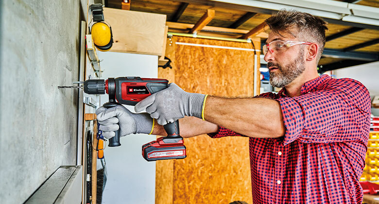 man using an impact driller to drill a hole in concrete