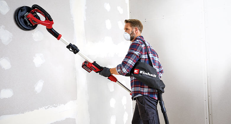 man working with a cordless drywall polisher
