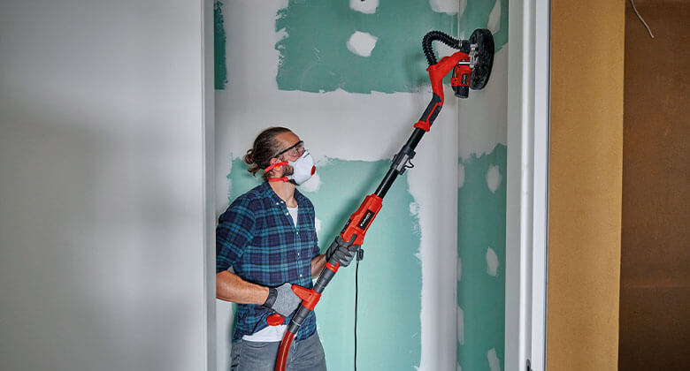 man working with a drywall sander